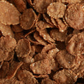 A close-up view of brown cornflake cereal pieces piled together, filling the entire frame.