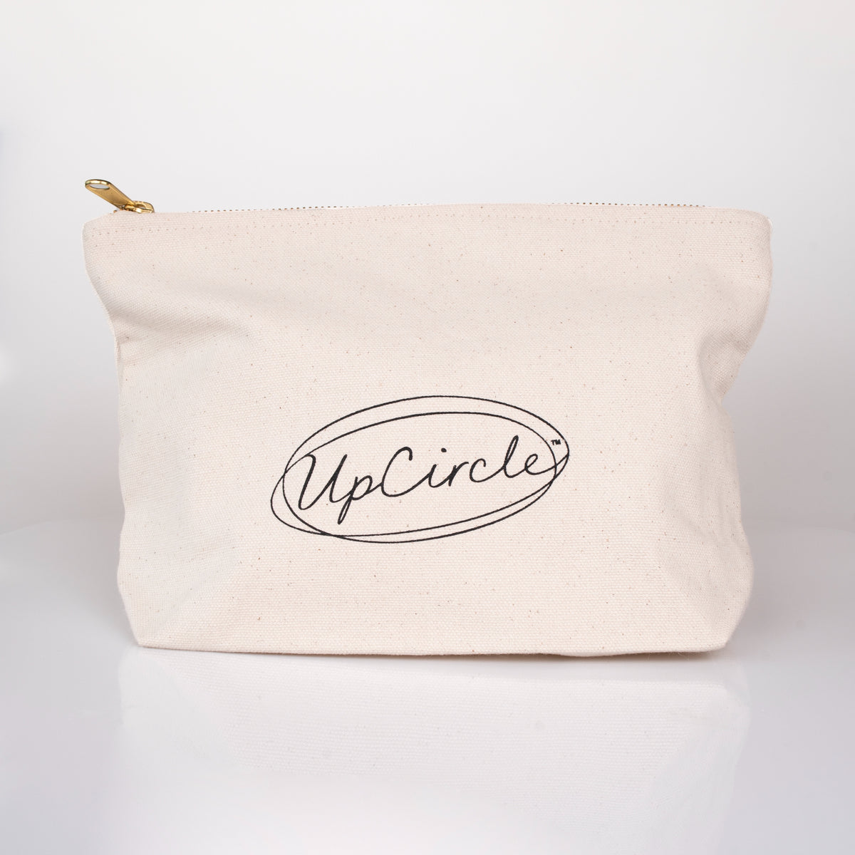 An off-white canvas cosmetic pouch with a gold zipper pull and a black printed 'UpCircle' logo, set against a clean white background.