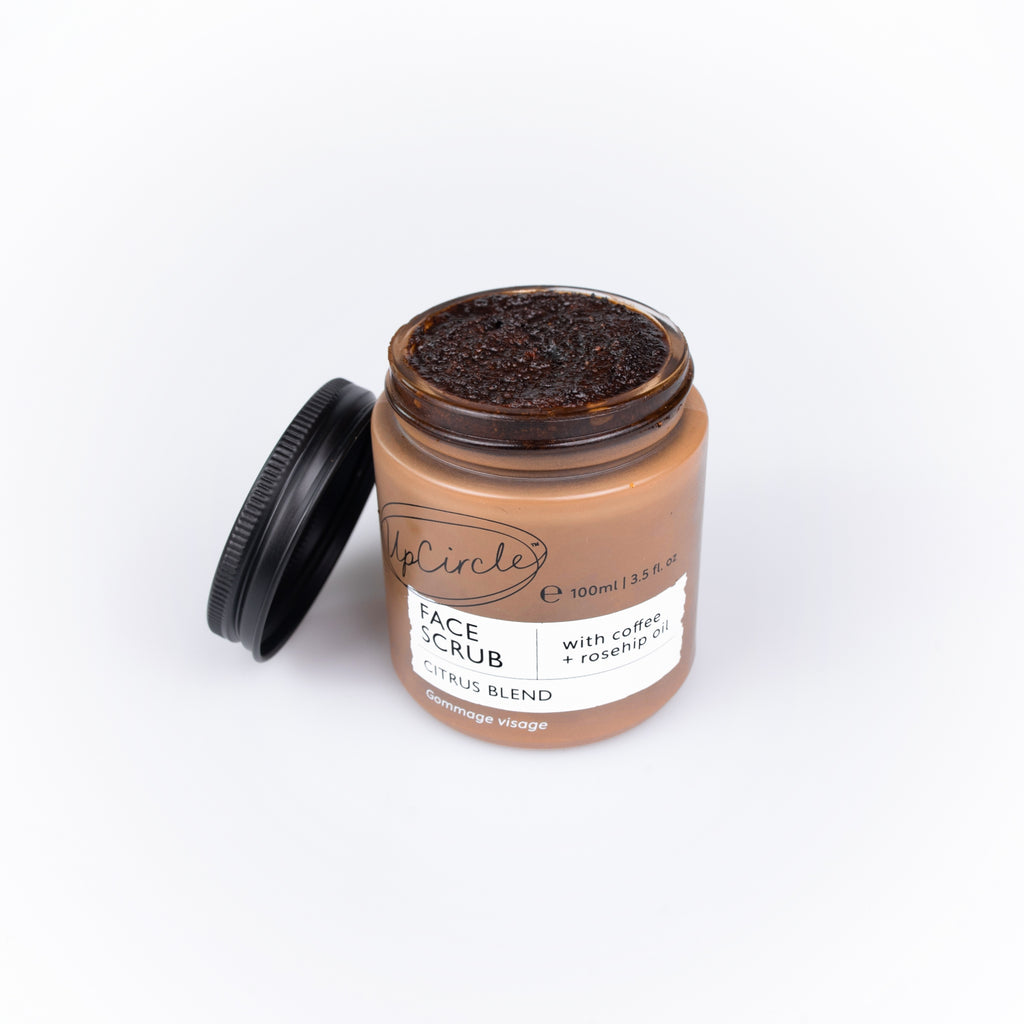 Jar of face scrub with a black lid on a white background