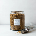 Jar of granola with a spoon on a white background