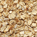A close-up texture shot of raw rolled oats filling the entire frame, showing individual flat, leaf-like grains in shades of beige and light brown.