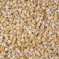 A close-up, top-down view of raw rolled oats filling the entire frame, showing their natural beige and light brown tones.