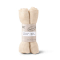 Two rolled beige muslin face cloths bundled together with a paper label.