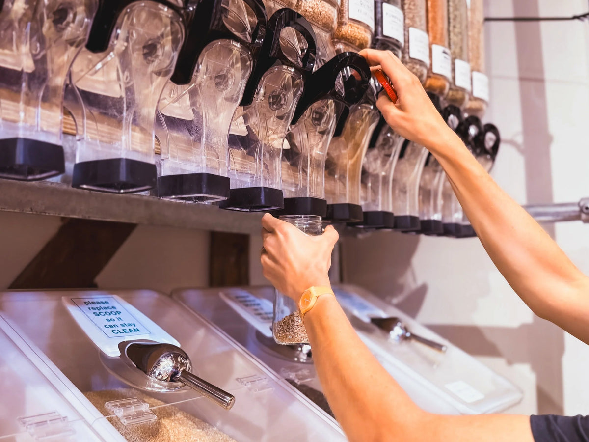 Person refilling their jar with sunflower seeds surrounded by other dispensers.