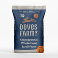 A 25 kg bag of Doves Farm Organic Stoneground Wholemeal Spelt Flour. The packaging is a dark navy blue with light gray accents at the top and bottom, featuring white text and illustrations of a rabbit, bee, and sun, with an orange circular '25 KG' badge in the bottom right corner.