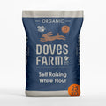 A 25 kg bag of Doves Farm Organic Self Raising White Flour, featuring a dark blue bag with white text and illustrations of a rabbit and sunflower, set against a clean white background.