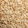 A close-up, top-down view of raw brown rice grains filling the entire frame.