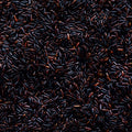 A close-up, top-down view of many small elongated dark brown to black grains or seeds densely packed together, filling the entire frame.