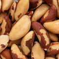 A close-up pile of Brazil nuts showing their characteristic cream-colored flesh with reddish-brown skin patches.