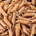 A high angle, close-up shows many penne pasta noodles filling the view. The pasta is ribbed and has open ends. 