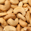 This is an extreme close-up shot showing a collection of cashew nuts. The creamy, tan-colored nuts create a pleasing pattern and inviting texture. 