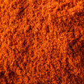 A close-up of bright orange-red ground cayenne pepper, filling the entire frame. 