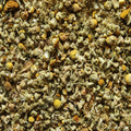 A close-up texture shot of dried chamomile flowers, showing the pale greenish-gray petals and bright yellow centers filling the entire frame.