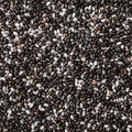 A close-up, top-down view of a mixture of black, dark brown, and white chia seeds filling the entire frame.