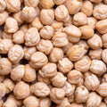 A close-up, top-down view of a pile of raw, shelled chickpeas filling the entire frame.