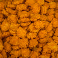 A close-up view of a pile of golden-brown, chilli rice crackers, filling the frame. 