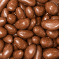 A close-up pile of glossy brown chocolate-covered brazil nuts filling the frame.