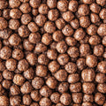 A close-up, top-down view of many small brown cereal-like balls or puffs filling the frame, with no person, animal, or real environment visible.