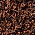 This close-up captures a dense pile of dried cloves, each showcasing its distinctive bulbous head and slender stem, filling the entire frame. 