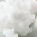 A close-up shot of fluffy white wax or solid cosmetic product, showing a soft, textured surface with soft shadows.