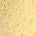 A wooden bowl filled with pale yellow cornmeal powder, filling the entire frame. 