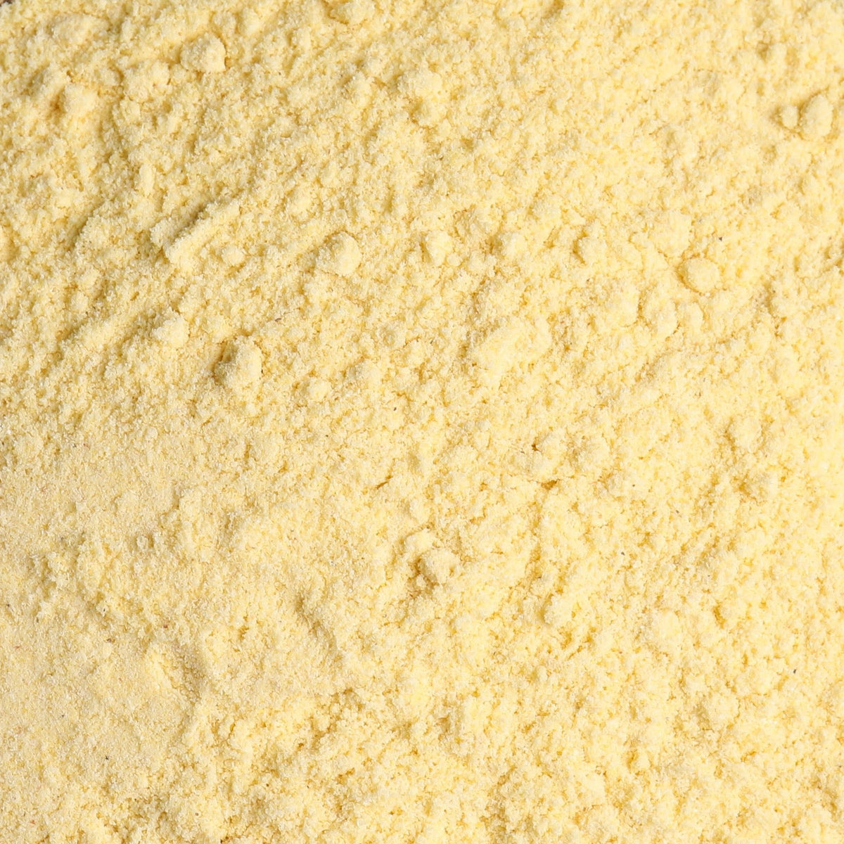 A wooden bowl filled with pale yellow cornmeal powder, filling the entire frame. 