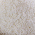 A close up shot shows a background of finely shredded coconut. The texture is rough and slightly coarse.