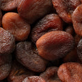 Natural unsulphured sun dried brown Turkish apricots fruit close up full frame as background.