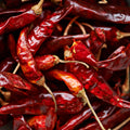 A close-up top-down view of dried red chili peppers filling the entire frame. 