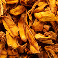This close-up photo showcases a pile of dried mango pieces. The mango pieces display a range of warm yellow, orange, and brown tones.
