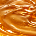 Close-up of a glossy amber liquid with a swirling texture and small bubbles, filling the frame.