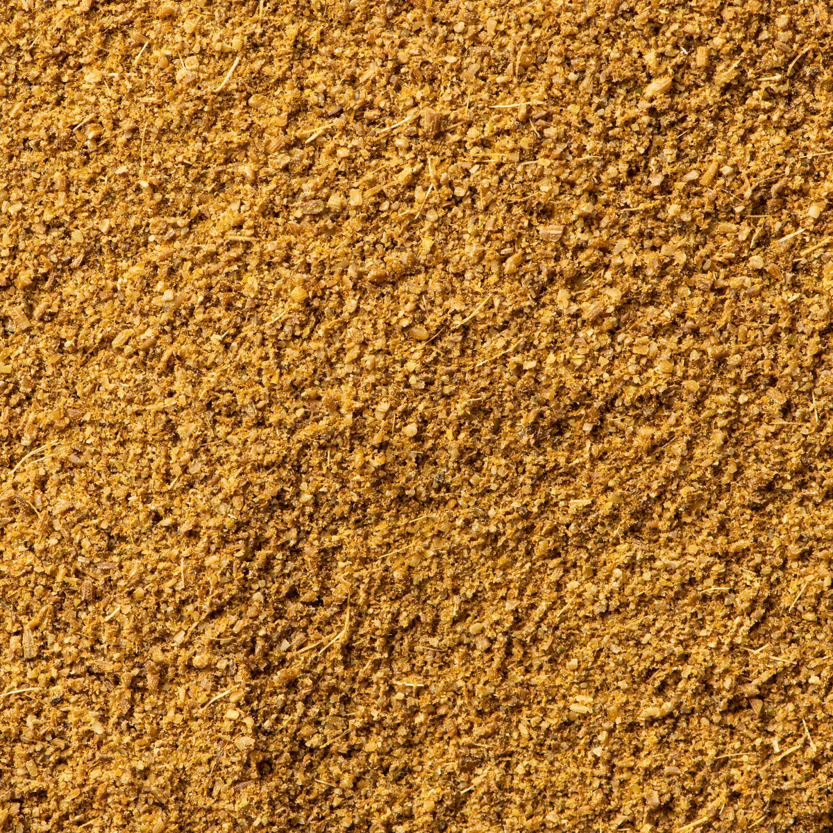 A close-up texture shot of a fine, granular golden-brown cumin powder, filling the entire frame. 