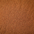 A close-up texture shot of a fine, granular ground nutmeg powder filling the entire frame.