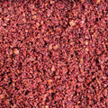 This detailed close-up shot presents a vibrant blend of spices, showcasing their rich textures and varied hues. The dominant color is a deep, earthy red, interspersed with hints of warm brown and scattered flecks of white. 