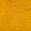 A close-up texture shot of a fine, granular yellow-brown powder, likely a spice or pigment, filling the entire frame.