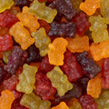 A close-up pile of gummy bear candies in assorted colors including orange, yellow, red, and dark purple, filling the entire frame.