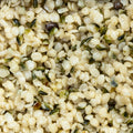 This macro-shot showcases a dense collection of hemp seeds, their husks partially removed revealing creamy white kernels with dark green flecks.