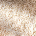 A close-up, top-down view of uncooked long-grain white rice grains filling the entire frame.