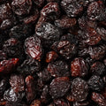 This tightly framed close-up captures a heap of plump, shiny brown Jumbo Flame Raisins, showcasing their wrinkly texture.