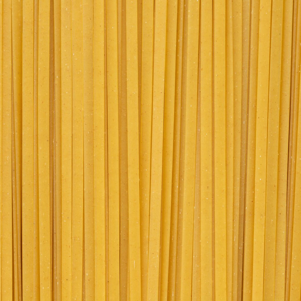 An abstract close-up of uncooked linguine pasta filling the entire frame. 