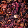 This striking close-up shot features a mixture of dried rosehips and hibiscus, creating a colorful and textured arrangement. The combination of reddish-brown rosehips and deep purple hibiscus petals creates a vibrant and visually appealing composition, highlighted by the natural daylight.