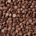 Close-up macro image of milk chocolate drops filling the entire frame. 