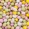 Close up photograph of a pile of chocolate mini eggs, all different colours filling the entire page.