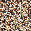 This close-up photograph shows a pile of uncooked quinoa seeds.