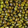 An extreme close-up shot showcases a wooden bowl filled with vibrant green mung beans.