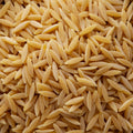 A close-up, top-down view of uncooked orzo pasta grains filling the entire frame.