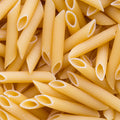 This close-up shot features a dense pile of uncooked penne pasta, showcasing their cylindrical shape and angled cuts. 
