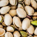 This extreme close-up photograph showcases a heap of pistachio nuts. 