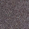 A close-up overhead view showcases a textured background made up of poppy seeds. The seeds are a mix of dark gray and brown, creating a natural and organic appearance