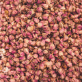 A close-up shows a large pile of dried rosebuds, tightly closed with pink coloration and brown stems. The overall composition has a muted light, enhancing the natural texture of the petals.